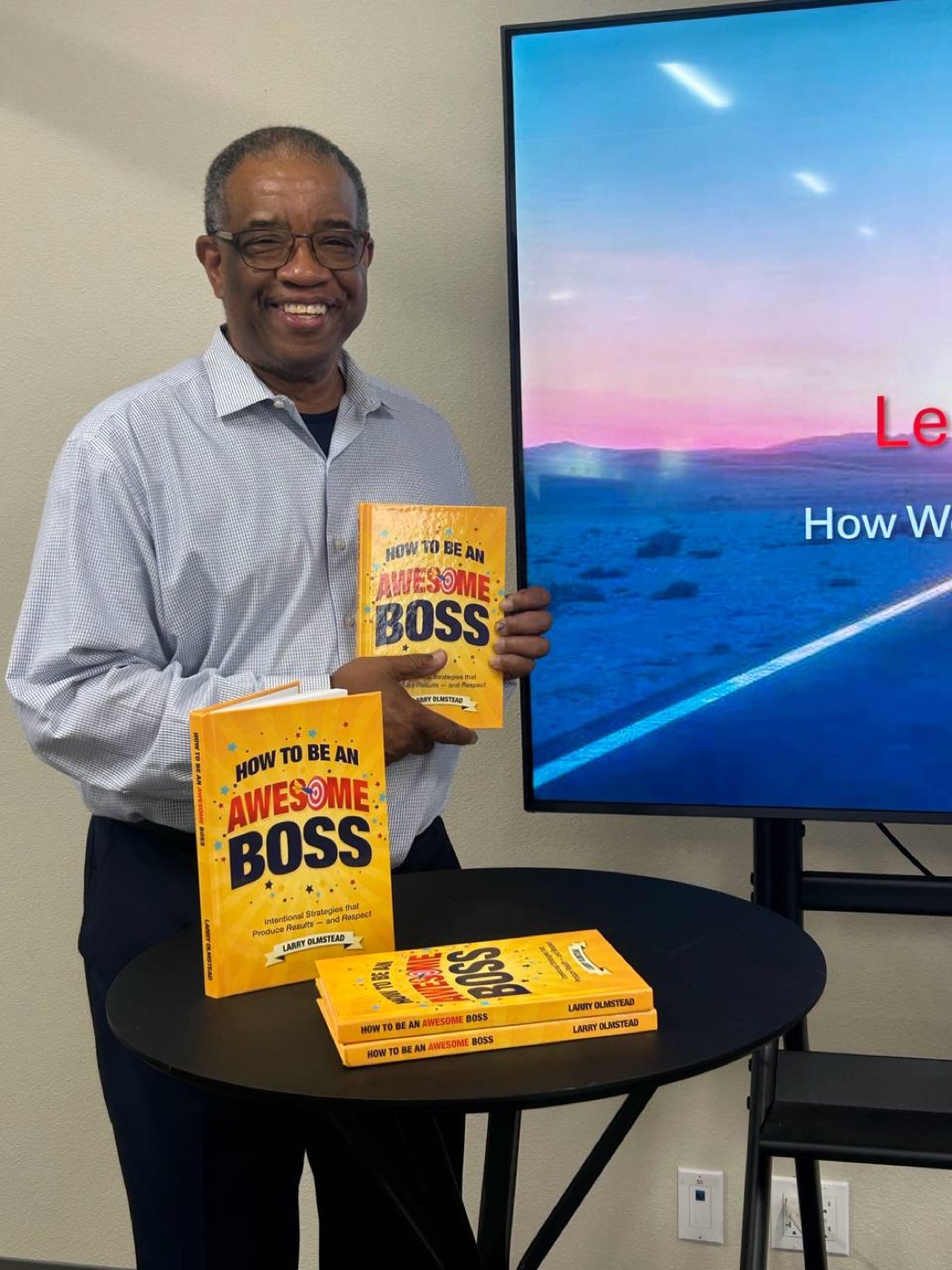 Larry Olmstead holding copies of How to be an Awesome Boss